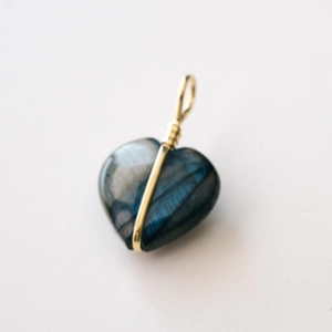 Detail van hartvormige labradoriet hanger met blauwe glans en gouden draadwikkeling