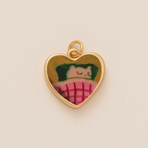 Golden heart-shaped pendant with sleeping cat illustration on pink checkered background