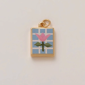Golden rectangular pendant with pink tulip and checkered pattern on light blue background
