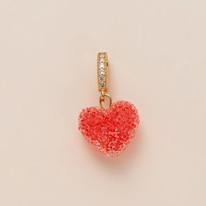 Macro detail of red textured heart pendant with a gold-plated cubic zirconia bail