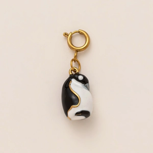 Detail of penguin pendant featuring black and white enamel finish with golden metal edges