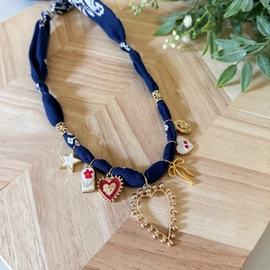 Dettaglio di collana in tessuto floreale blu scuro con ciondoli dorati e smalto