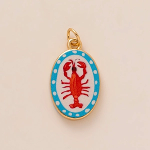 Detail van een ovale kreeft hanger met rood emaille, blauwe stippen en gouden frame
