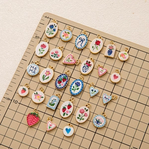 Buntes Emaille-Anhänger-Set mit Herzen und Blumen auf einem Gitterhintergrund