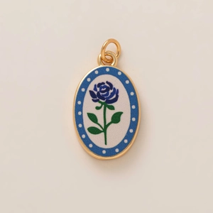 Oval gold pendant with blue rose floral design and blue polka dot border
