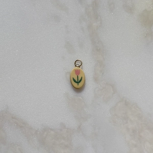 Detailed view of an oval tulip pendant with pink enamel flowers on a golden metal loop