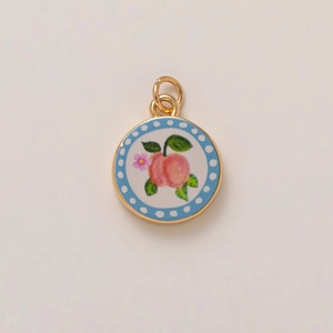 Golden round pendant with a pink peach and flower design on a light blue dotted border