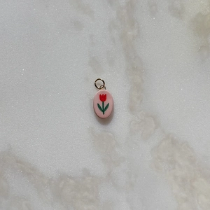Macro detail of oval pink tulip pendant with golden ring on marble background
