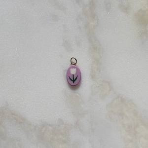 Detail of oval purple pendant with white tulip design on grey marble background