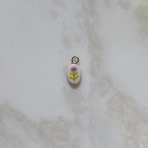 Floral oval pendant with purple flowers on white ceramic surface and metal ring