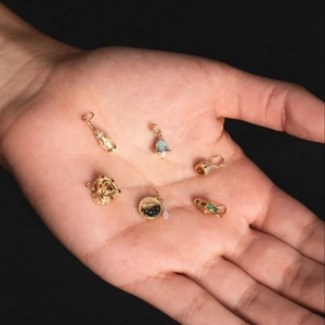 Ciondoli in zircone colorato placcati oro 14K in varie forme su mano con sfondo nero
