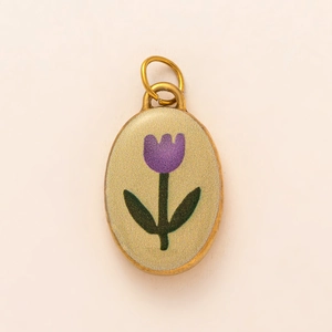 Dettaglio di un ciondolo ovale con tulipano in smalto viola e bordi placcati oro