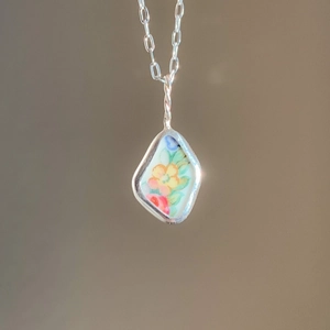 Artistieke porseleinen bloemenhanger met geometrisch 18K gouden frame en zilveren ketting