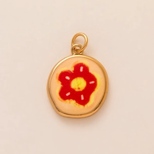 Detail of round gold-plated pendant with red and yellow enamel flower pattern