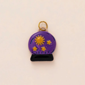 Détail du pendentif boule de cristal en émail violet avec soleil et étoiles