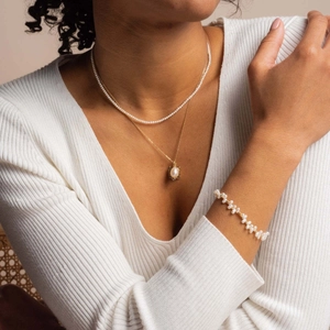Detailed view of 14k gold layered necklaces and a bracelet with white freshwater pearls