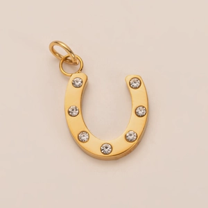 Macro shot of horseshoe pendant in 18K gold finish with seven clear inlaid crystals