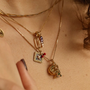 Close-up of layered 14k gold-plated necklaces with enamel love pendants and zircon accents