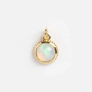 Detail of 14k gold geometric pendant with iridescent opal and beaded edge finish