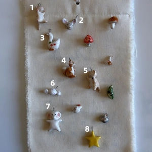Close-up detail of various forest-themed ceramic animal and star pendants on fabric