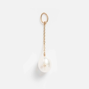 Macro detail of 14k gold geometric pendant featuring a white pearl with starburst inlay
