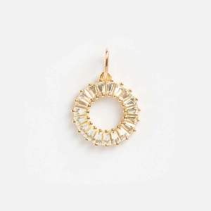 Detail of a 14k gold-plated round pendant with baguette-cut zircon and sunburst design
