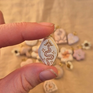 Macro detail of a bohemian rhombus pendant featuring a purple snake and gold star pattern
