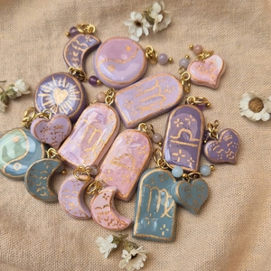 Handmade clay flower pendants with celestial symbols on rustic linen background