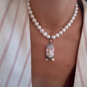 Close-up of pearl necklace with hand-painted elephant pendant on a model in a beige suit