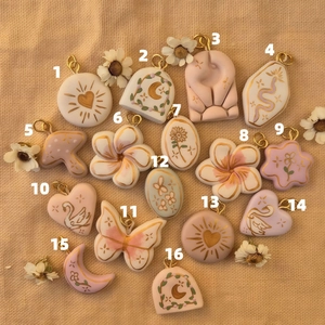 Flat lay of 16 assorted floral and animal patterned pendant charms for DIY jewelry making