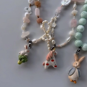Detail of beaded necklaces with colorful rabbit and horse pendants in ceramic enamel