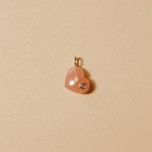 Macro detail of a pink heart gemstone pendant with a gold starburst and crystal setting