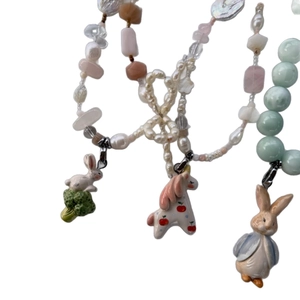 Beaded necklace with ceramic rabbit and unicorn charms, featuring pearls and pink crystals