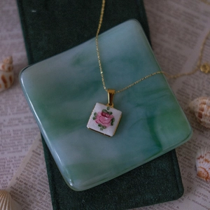 Détail du pendentif carré blanc avec rose rose sur velours et pierre de marbre
