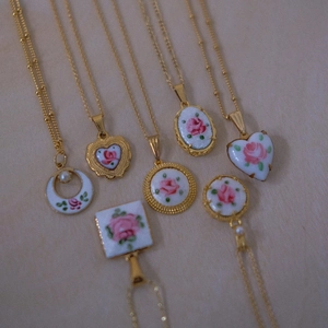 Colliers vintage plaqués or 14K avec pendentifs à motif rose et perles sur fond beige