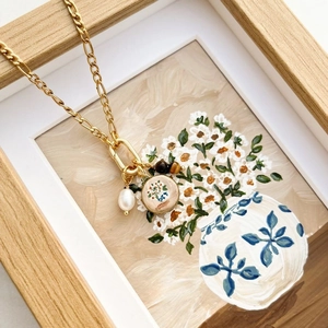 Collar de cadena Figaro con perlas y dijes florales sobre un marco de madera vintage