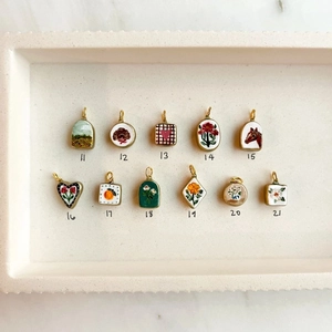 Detalle de 11 colgantes de esmalte con motivos florales y animales con borde dorado