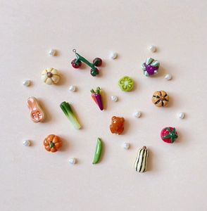 Flat lay of miniature ceramic vegetable charms and a roast chicken on beige background