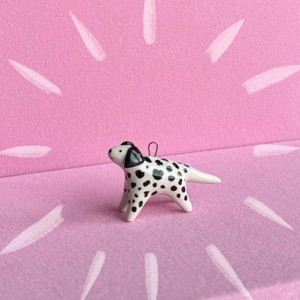 Close-up of a white Dalmatian dog charm with black spots and a polished glazed finish