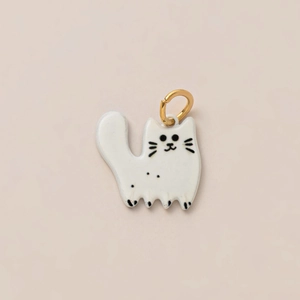 Detail eines minimalistischen Katzenanhängers aus Keramik mit goldenem Ring auf Rosa