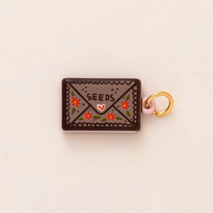 Vue détaillée d'un pendentif enveloppe en céramique avec texte SEEDS et motif cœur