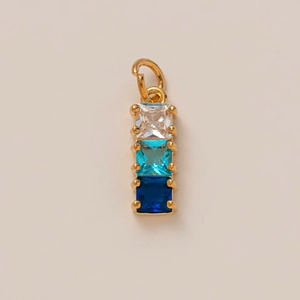 Macro shot of 18k gold plated pendant with gradient square crystals in blue and clear colors