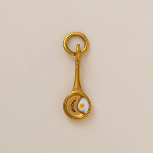 Vista macro di un ciondolo creativo a forma di padella con uovo in oro 18K per gioielli