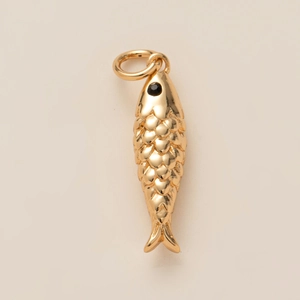 Détail macro d'un pendentif poisson doré avec des textures d'écailles et un œil noir