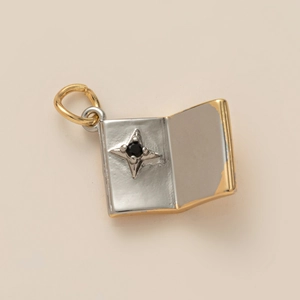 Détail d'un pendentif en forme de livre bicolore avec motif étoile et pierre noire