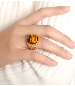 Macro shot of tiger eye stone ring with vintage woven texture on gold plated band