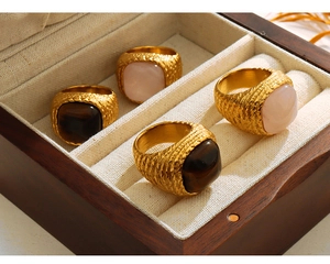 Close-up of geometric woven gold rings set with natural pink and tiger eye stones