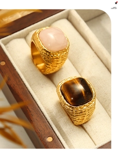 Close-up of gold woven texture rings featuring pink quartz and brown tiger eye stone