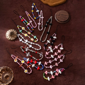 Handmade beaded phone charms with colorful acrylic hearts and clouds on a matte surface