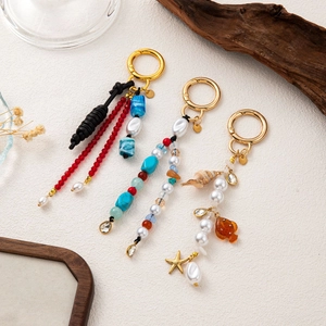 Bohemian beaded keychains with starfish and fish charms on elegant stone texture